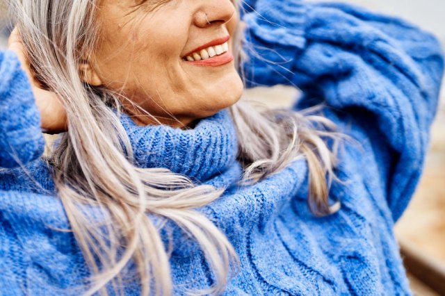 A woman with gray hair wearing a vibrant blue sweater