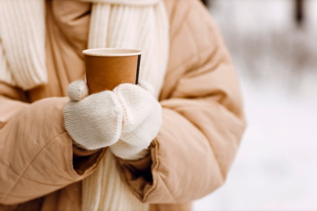 An image of a person in a parka holding a to-go cup of coffee