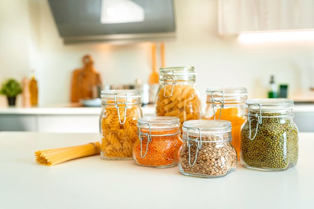 An image of pasta and beans in clear jars on a kitchen counter