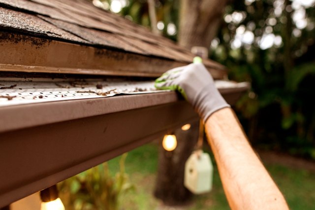 An image of a person cleaning out the gutters