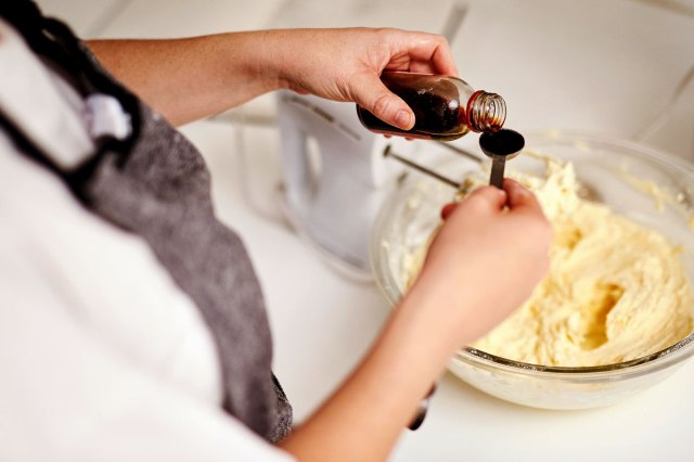 An image of a person pouring vanilla onto a measuring spoon