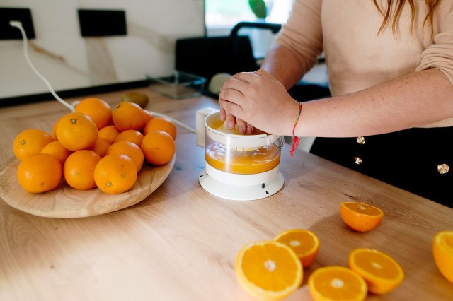 An image of a woman making fresh orange juice