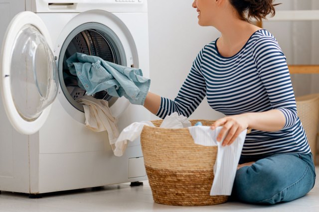 An image of a woman taking clothes out of the dryer