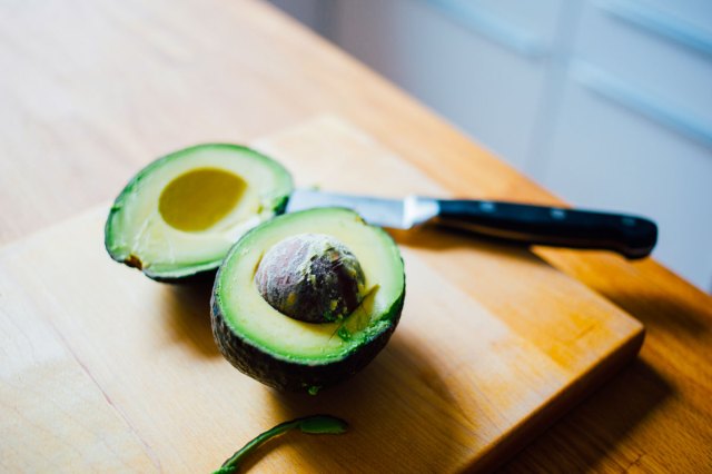An image of two avocado halves on a wooden cutting board