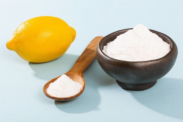 An image of a lemon, a wooden spoon with salt, and a brown bowl with salt