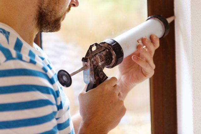 An image of a man caulking a window frame