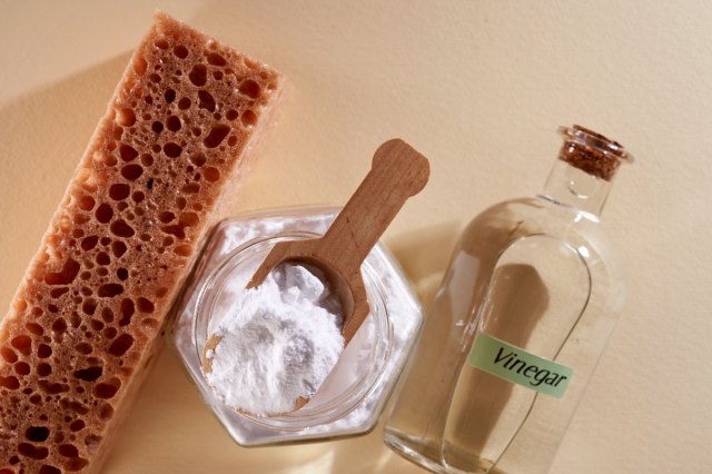 An image of a brown sponge, baking soda, and a bottle of vinegar