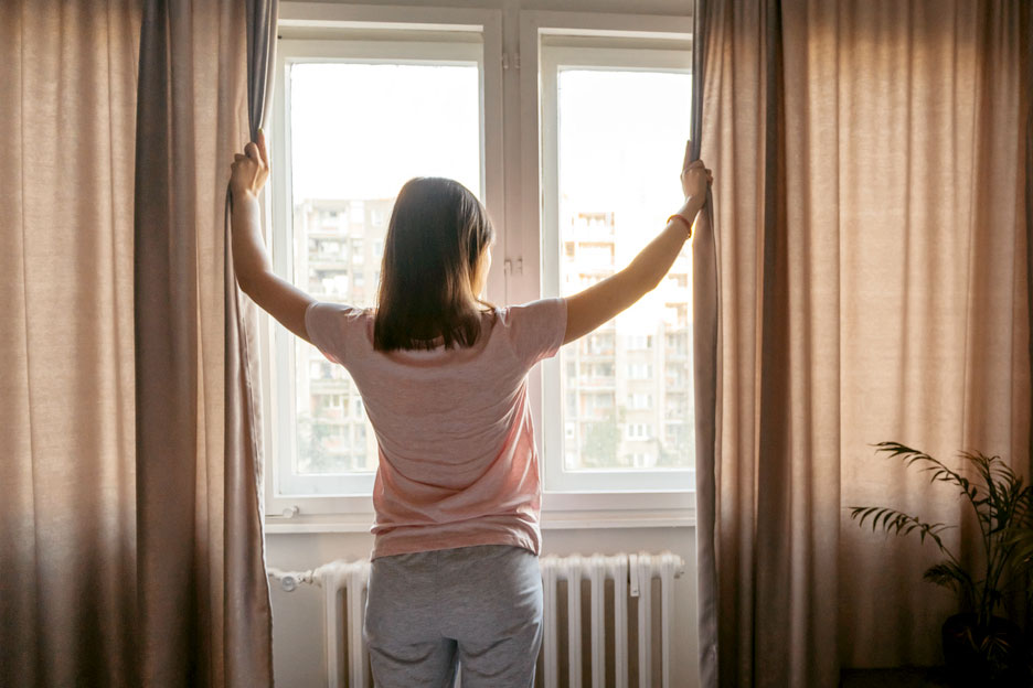 An image of a woman opening curtains