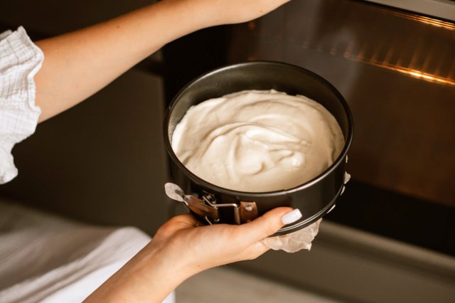 An image of a cheesecake being put in an oven
