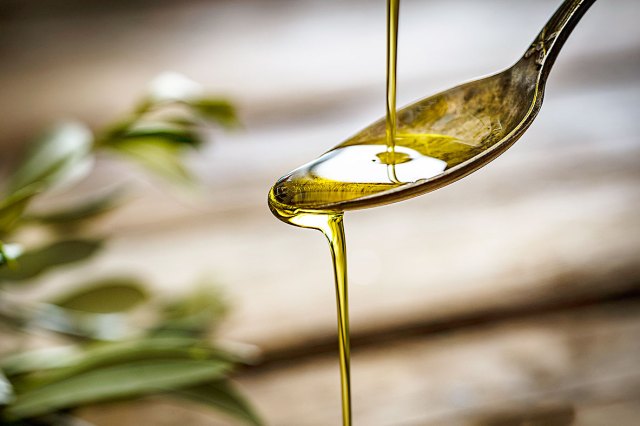 An image of oil being poured onto a spoon