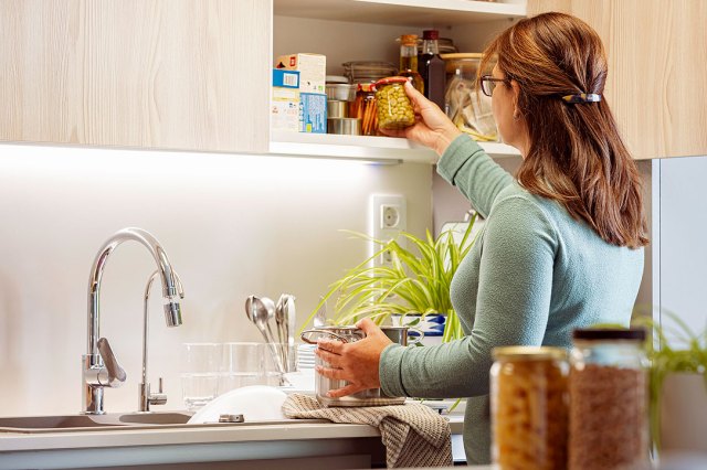 An image of a woman taking a jar out of a pantry