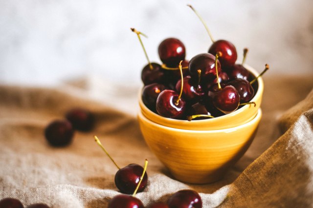 An image of a yellow bowl filled with cherries