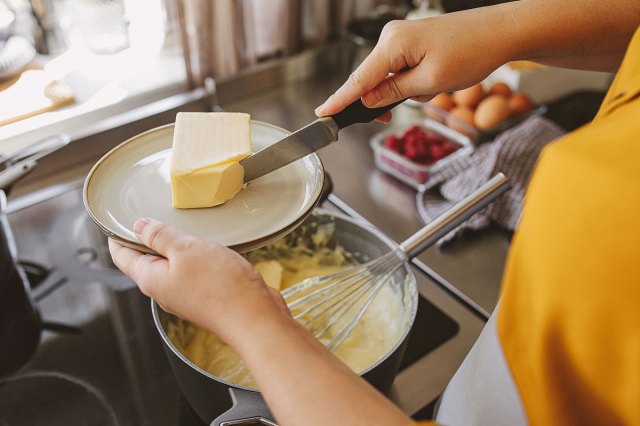An image of a person putting butter into a pot