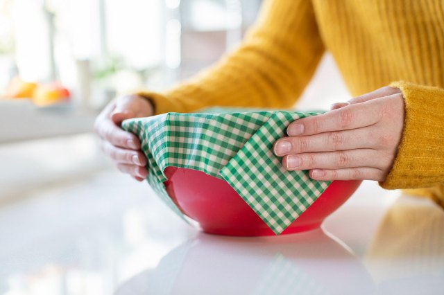 An image of a person putting a green and white cloth over a red bowl