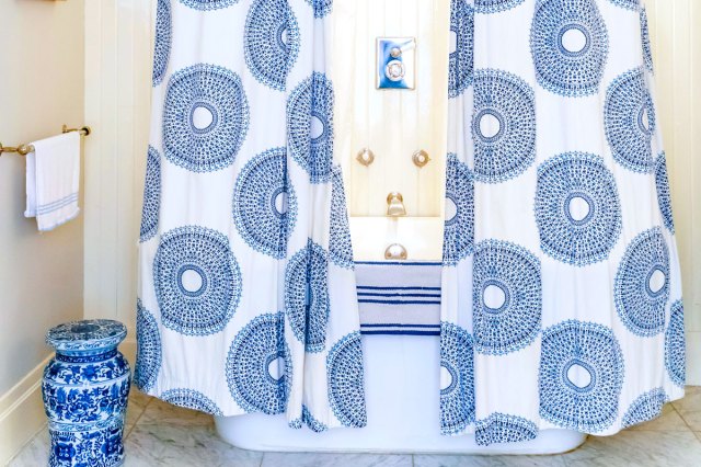 An image of a blue and white shower curtain around a blue and white bathtub