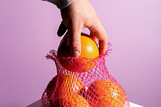 An image of a hand taking an orange out of a bag