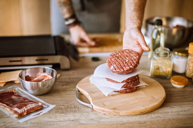 An image of a person taking a hamburger off a stack