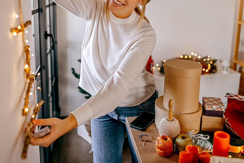 An image of a woman decorating a room with lights