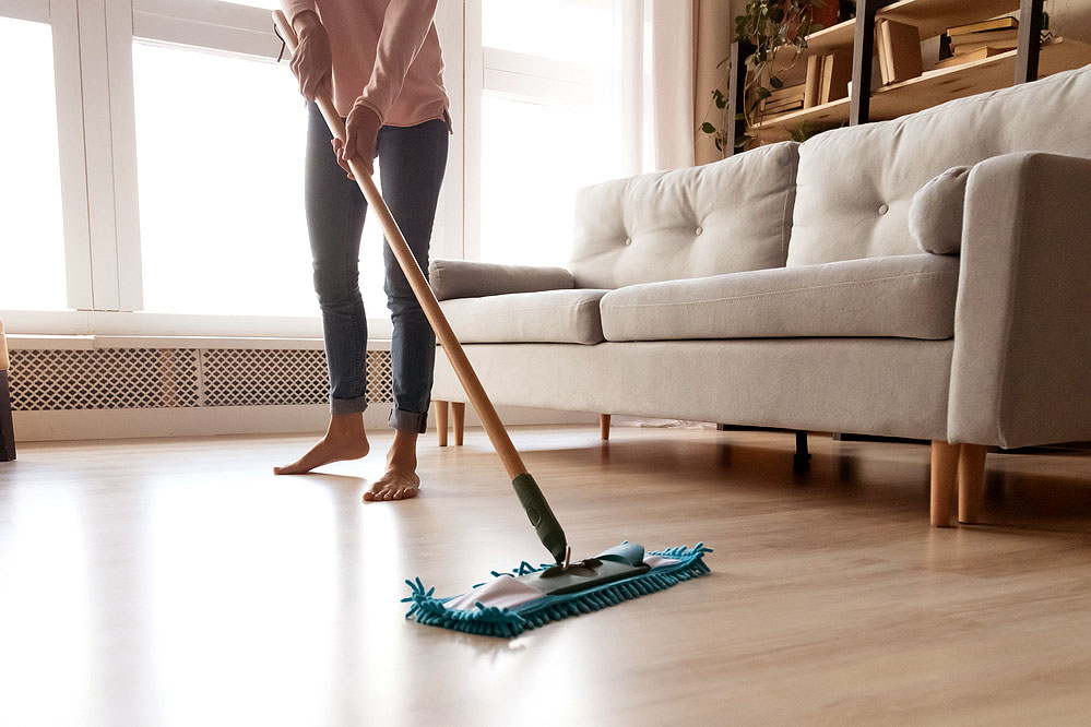 An image of a woman mopping a wood floor in a living room