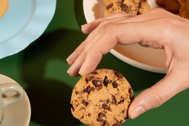 An image of a hand holding a chocolate chip cookie