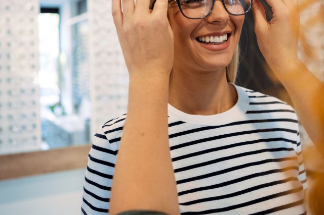 An image of a woman trying on glasses