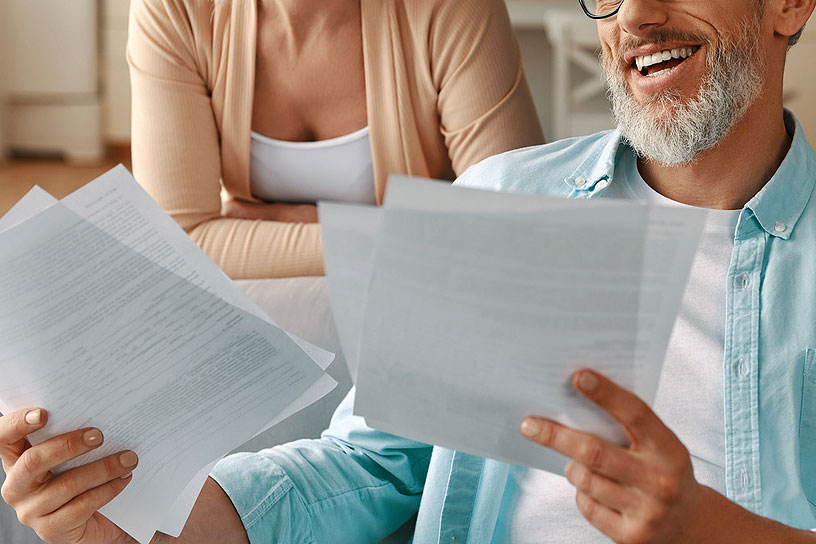 An image of a man and a woman looking at papers and smiling