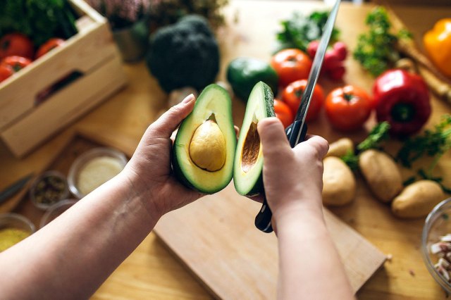 An image of a person holding two halves of an avocado