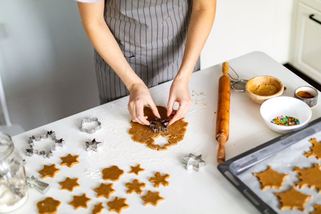 An image of a baker cutting cookies out of dough with a cookie cutter