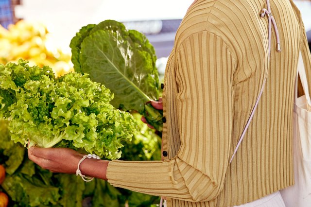 An image of a woman holding two bunches of kale