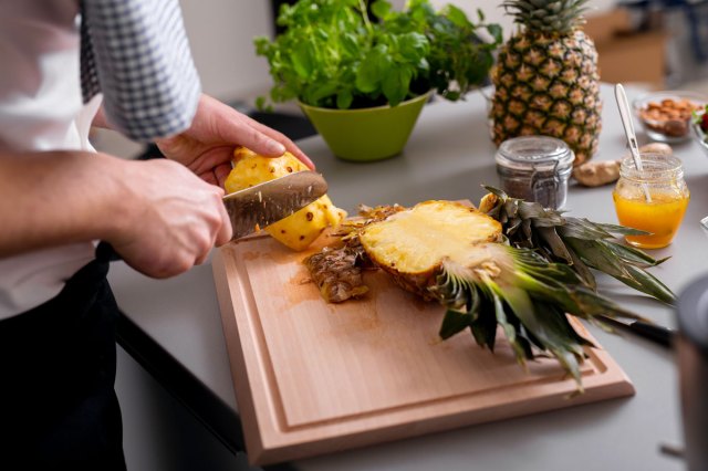 An image of a person cutting a pineapple