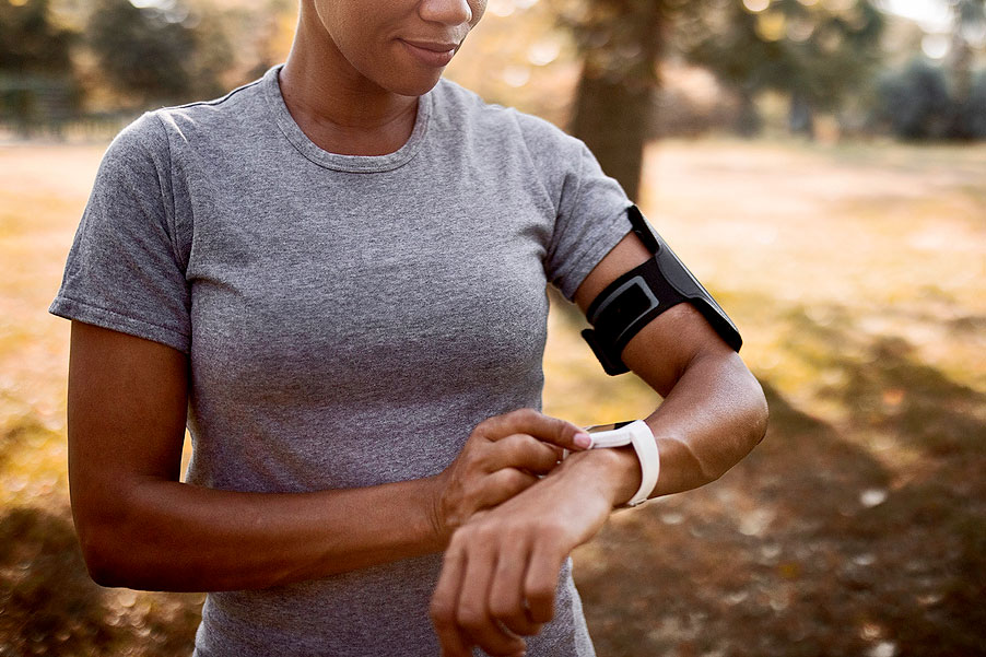 An image of a woman looking at her smart watch while working out outside