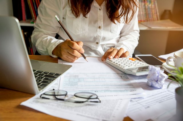 An image of a woman sitting at a desk doing her taxes