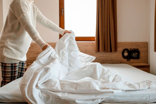 An image of a woman making the bed