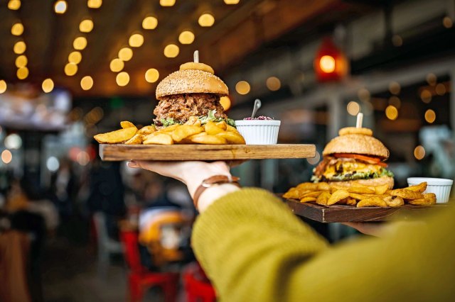 An image of a server holding two plates with hamburgers and fries