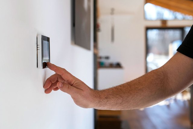 An image of a man adjusting the thermostat