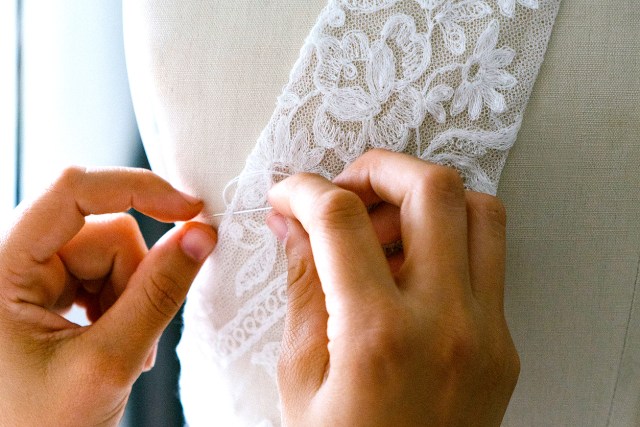 An image of a person sewing white lace