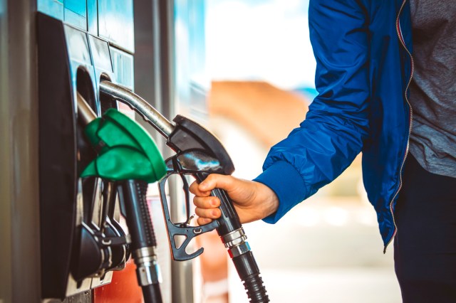 An image of a man putting a gas nozzle back