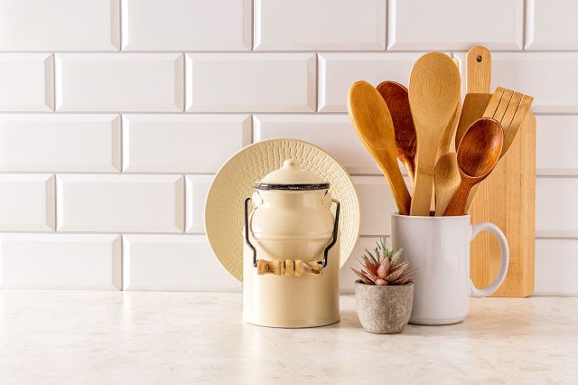 An image of a kitchen counter with a cookie jar, succulent plantm and a white mug with wooden utensils