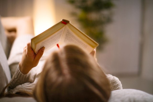 An image of a person lying down and reading a book