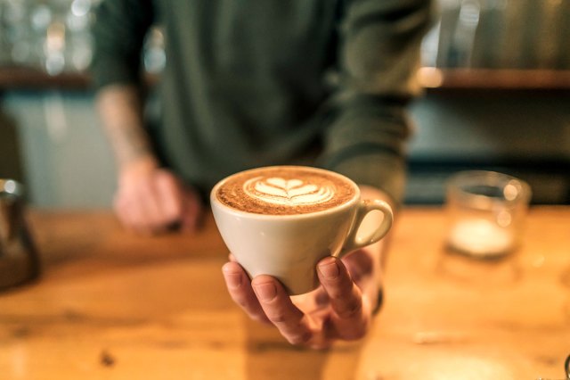 An image of a barista holding a cappuccino