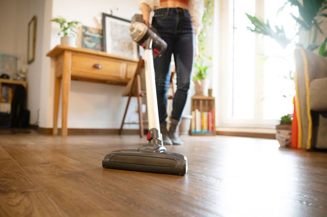 An image of a woman vacuuming a hardwood floor