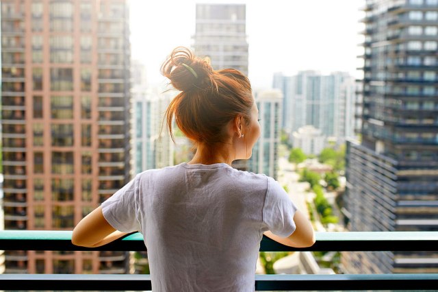 An image of a woman on a balcony overlooking a city