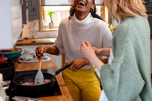 An image of two women laughing while cooking