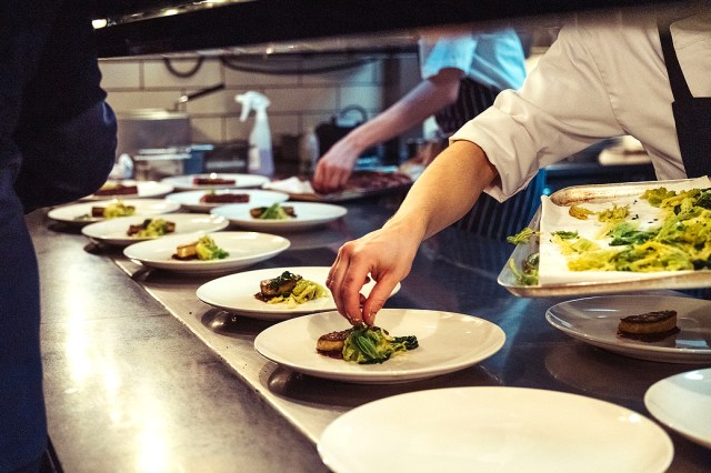 An image of chefs putting food on plates at a restaurant