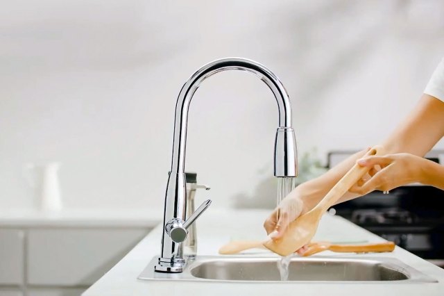 An image of a person washing wooden utensils in the sink