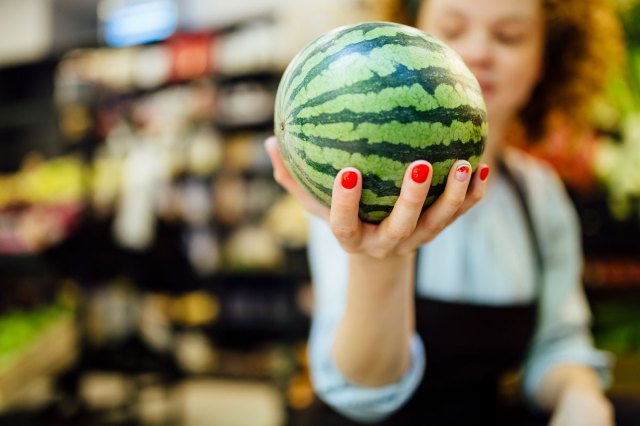 An image of a grocery store worker holding a watermelon