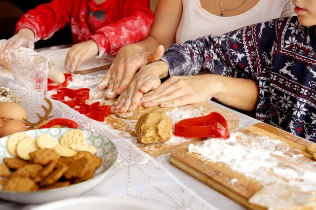 An image of three people making cookies with cookie cutters