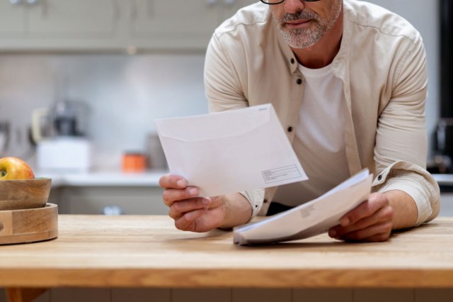 An image of a man leaning on the counter, looking at the mail
