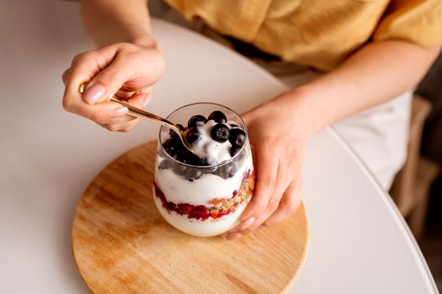 An image of a woman dipping a spoon into a yogurt parfait