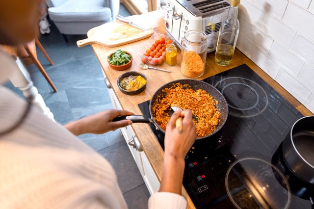 An image of a person cooking a pan of beans on the stove
